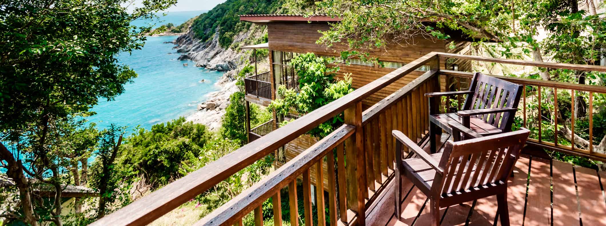 two wooden chairs on a porch overlooking a beautiful, lush landscape