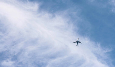 A lone airplane flying through a bright blue sky