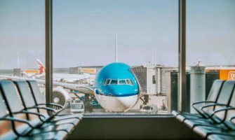 A blue commercial aircraft parked at the gate in an airport