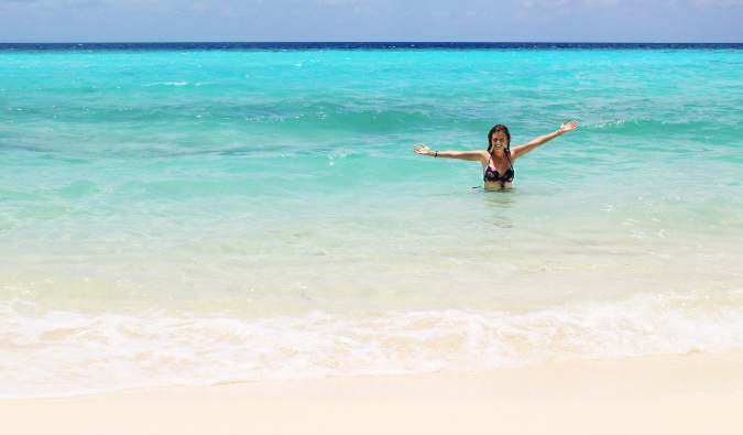 Female traveler swimming in the clear water in the Maldives