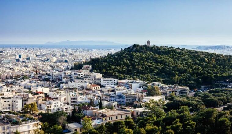 Athens cityscape with white buildings and large, forested hill