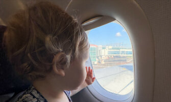 A young baby looking out a small airplane window