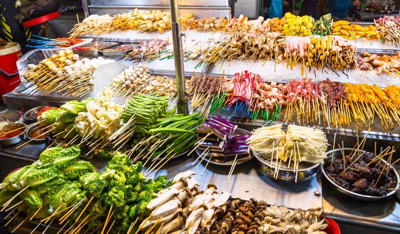 Skewers of meat lined up over a grill at a street stall in Bangkok, Thailand