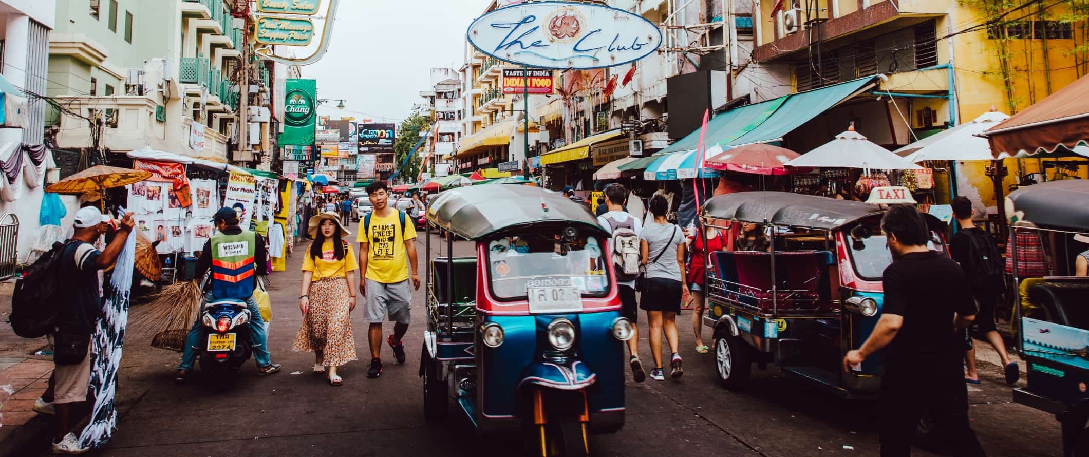 Busy street in Bangkok, Thailand filled with people and rickshaws