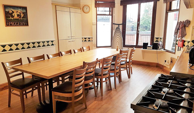 Kitchen area with long wooden table and bay windows at Barmy Badger, London