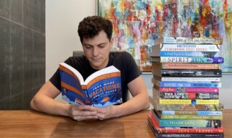 Nomadic Matt reading a pile of books inside at a big desk