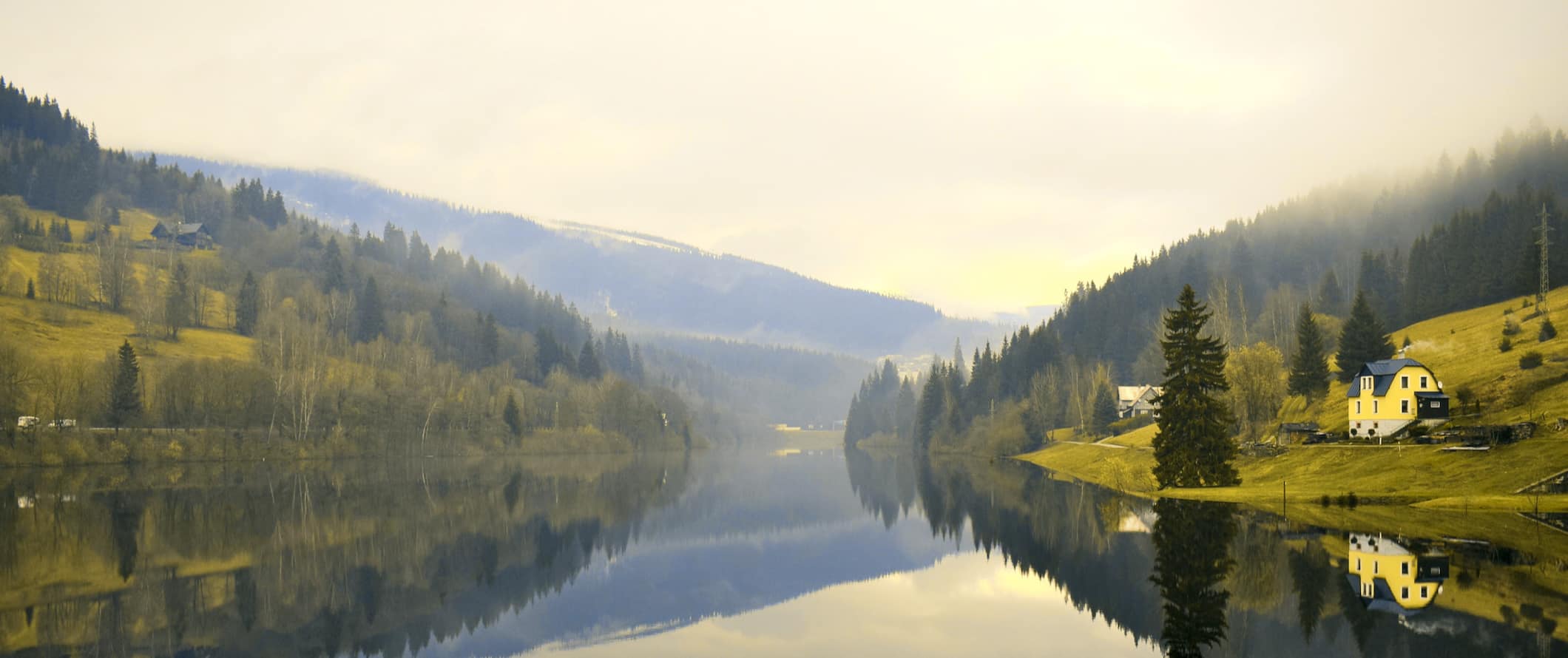 A calm lake surrounded by rolling hills in rural Czechia