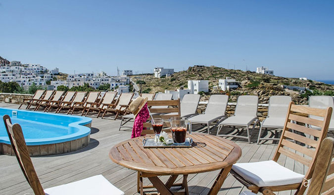 Pool with deck chairs and view of white houses on hills in the background at Francesco's hostel in Ios