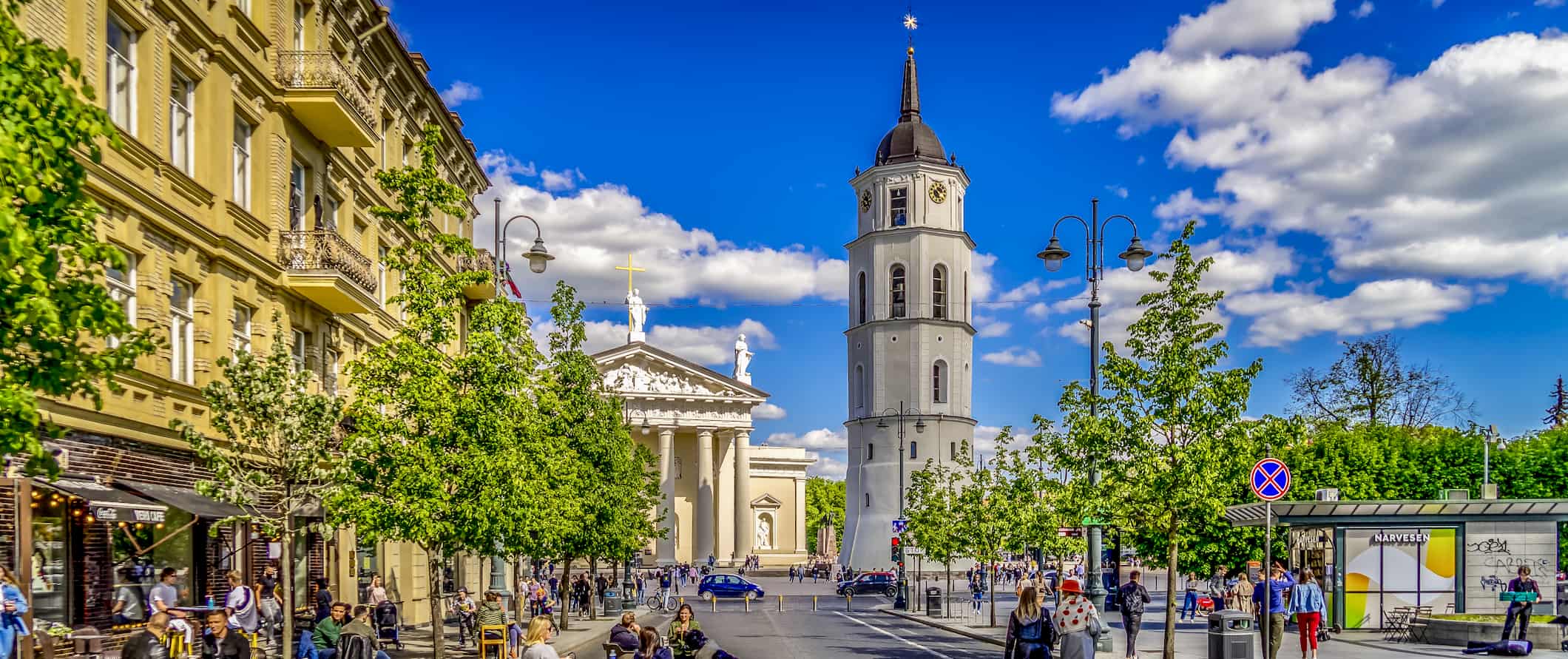 Historic buildings surrounded by lush, greens forests in Lithuania on a sunny day