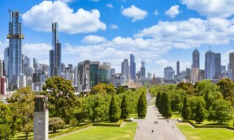 People exploring a wide-open park near the war memorial in sunny Melbourne, Australia