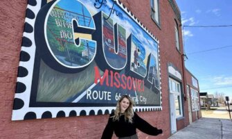 Travel blogger Raimee Iacofano posing near a mural in Cuba, MO on a Route 66 road trip