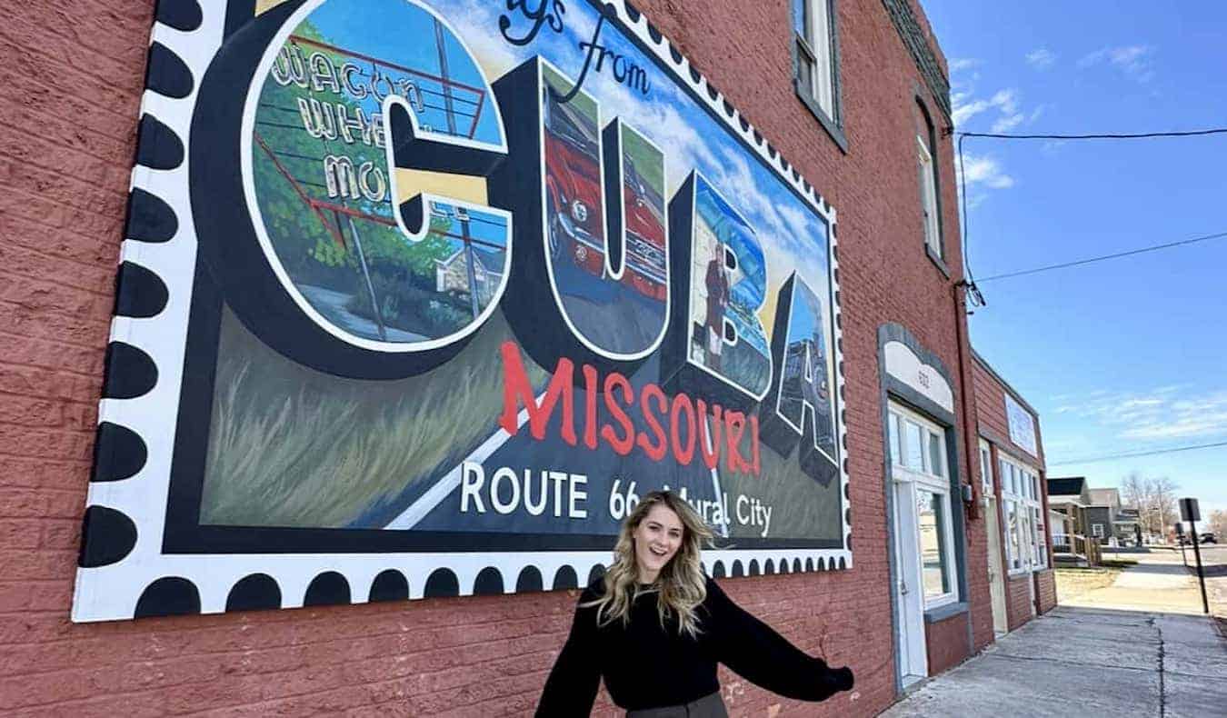 Travel blogger Raimee Iacofano posing near a mural in Cuba, MO on a Route 66 road trip