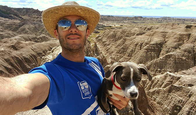 Portrait shot of Scott holding a dog taking a selfy in nature