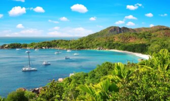 Sailboats in a tranquil bay surrounded by lush rolling hills in the Seychelles