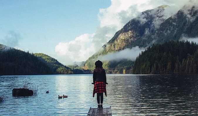 A woman on a dock overlooking a mountain lake