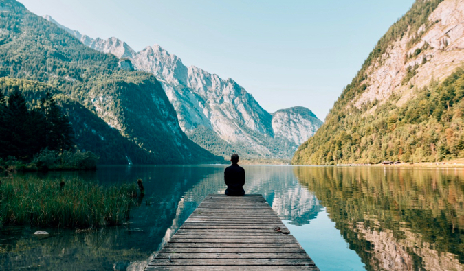 A traveler sitting on a dock surrounded by nature