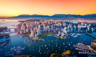 the stunning skyline of Vancouver, Canada as seen from above at sunset with mountains in the distance