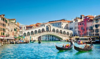 A sunny day in Venice, Italy as people ride gondolas in the large canals