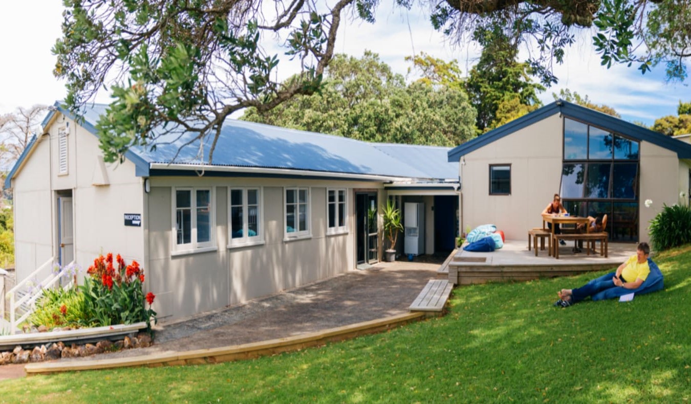 People lounging on the lawn in front of Waiheke Backpackers Hostel in Auckland, New Zealand