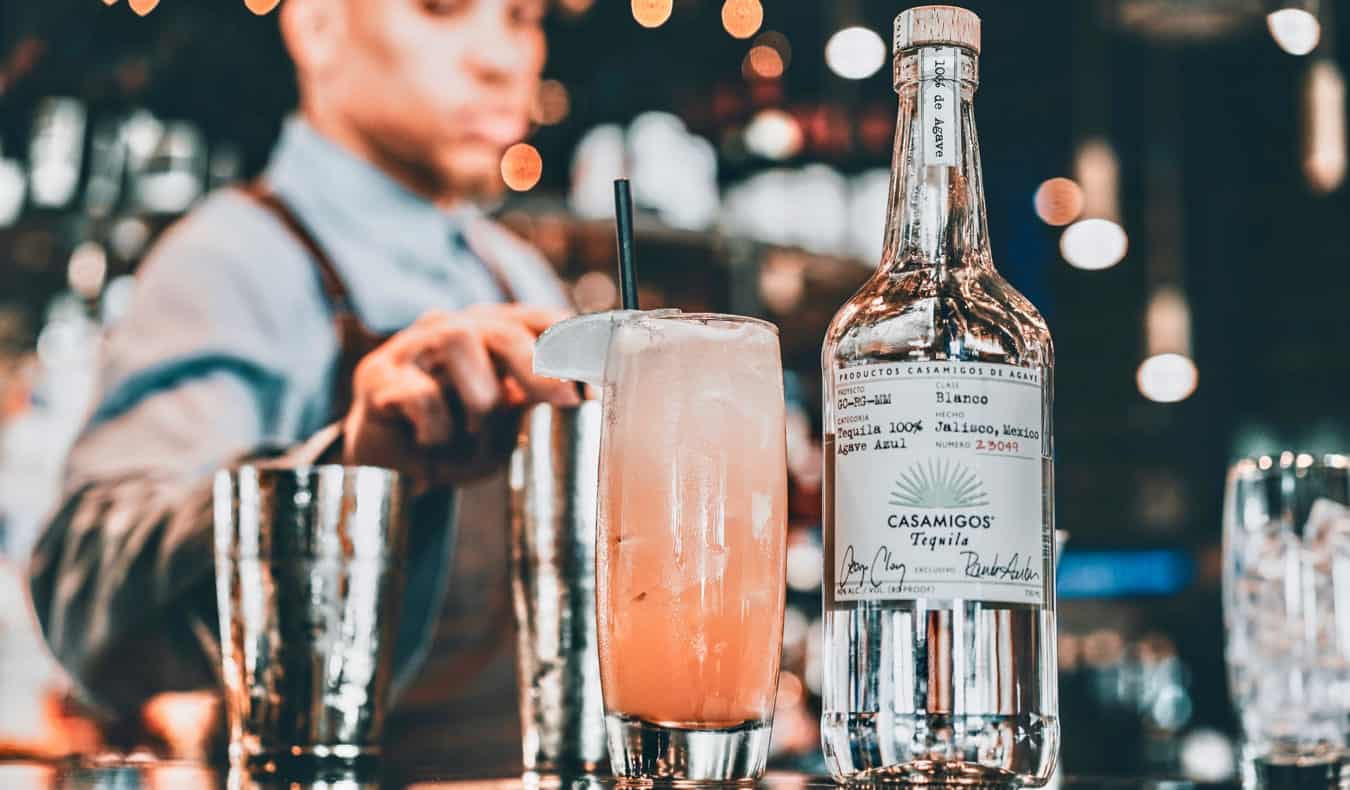 A bartender and an expensive tequila drink at a dimly-lit bar