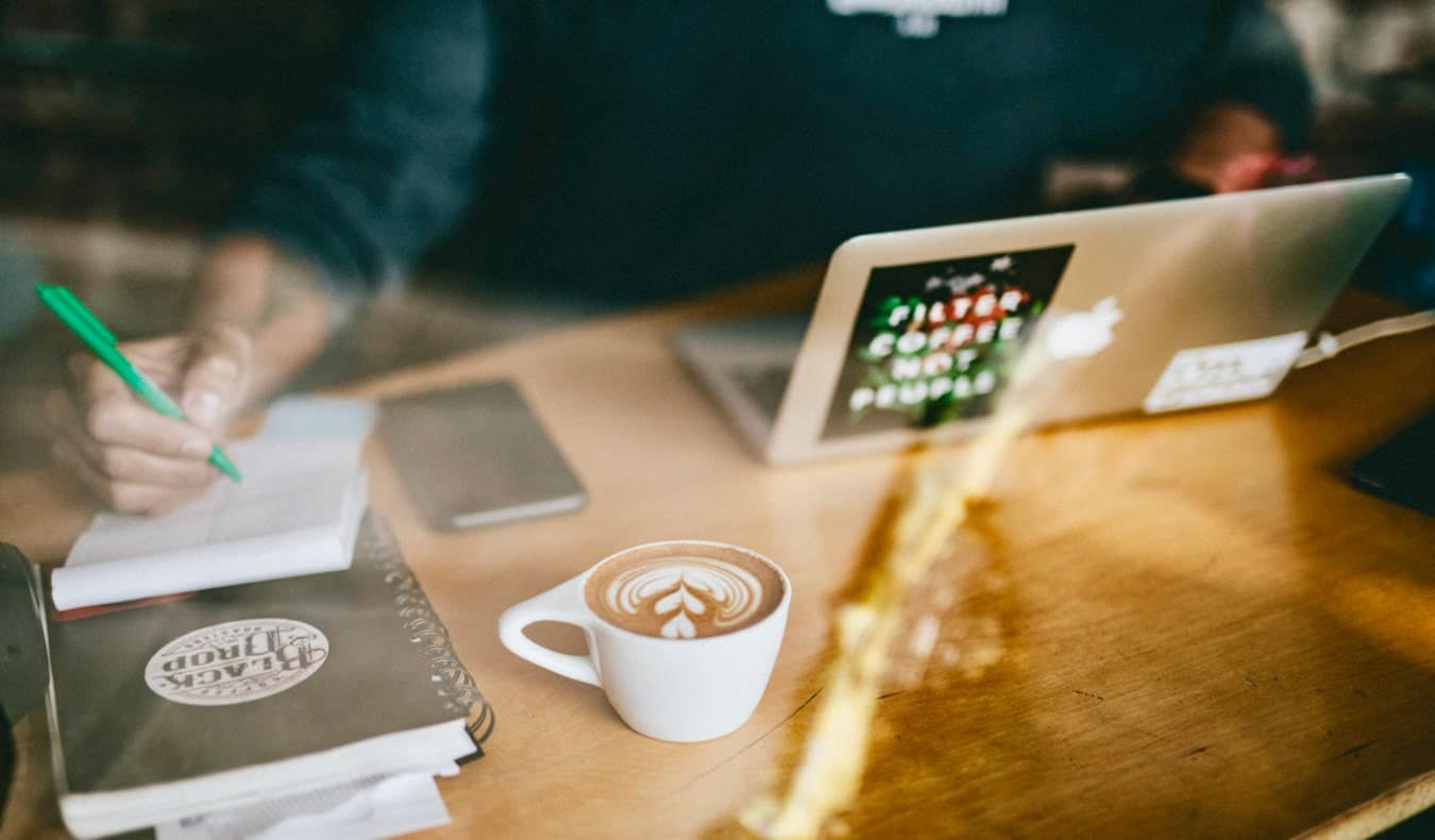 A man working online at a cafe while drinking a latte